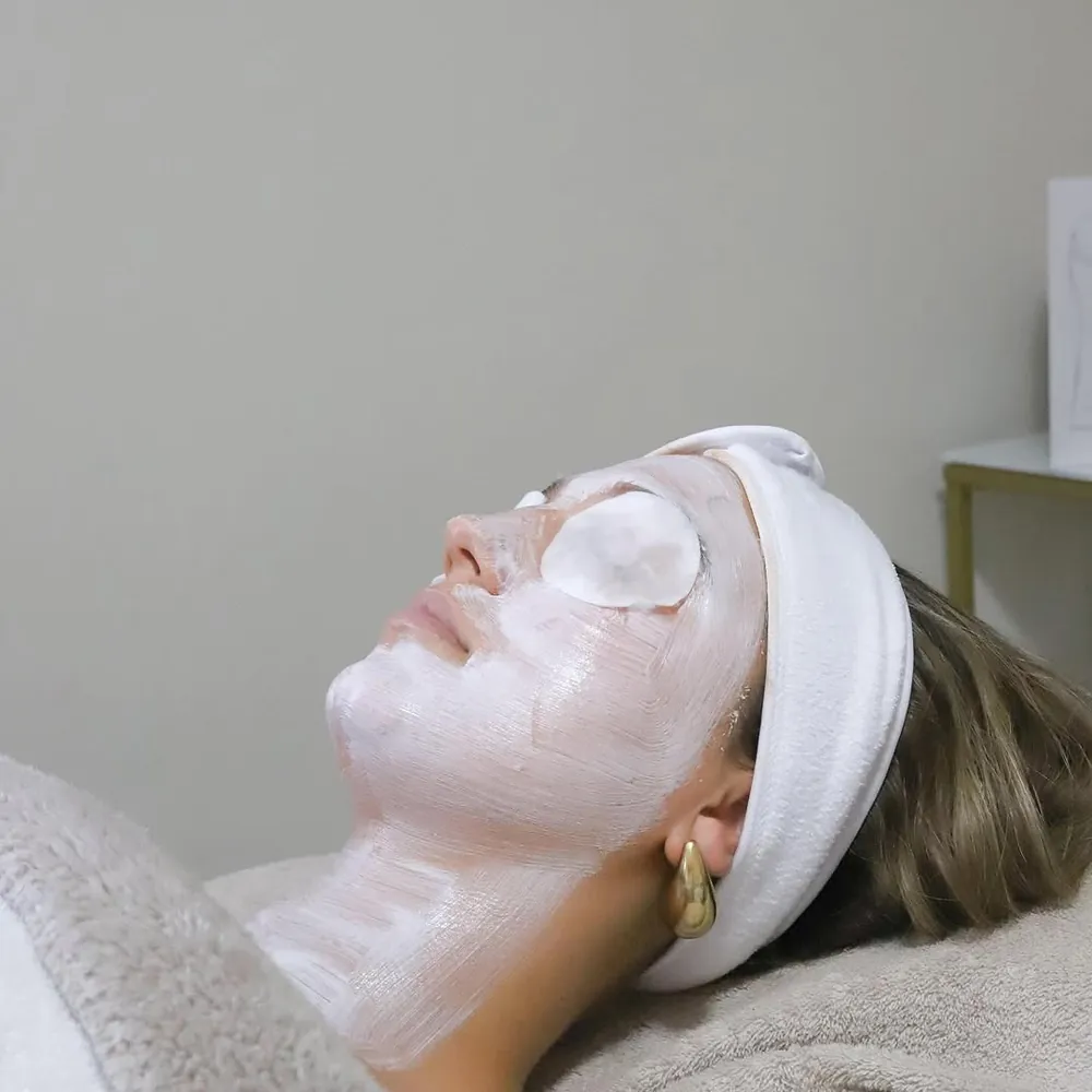 Klant met verzorgend masker en oogpads tijdens een gezichtsbehandeling