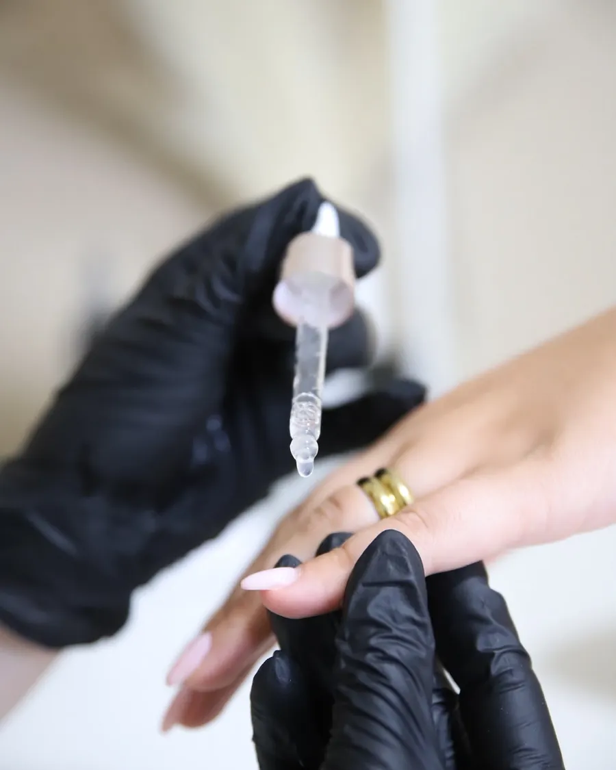 Verzorgende nagelriemolie wordt met een pipet aangebracht tijdens de manicure